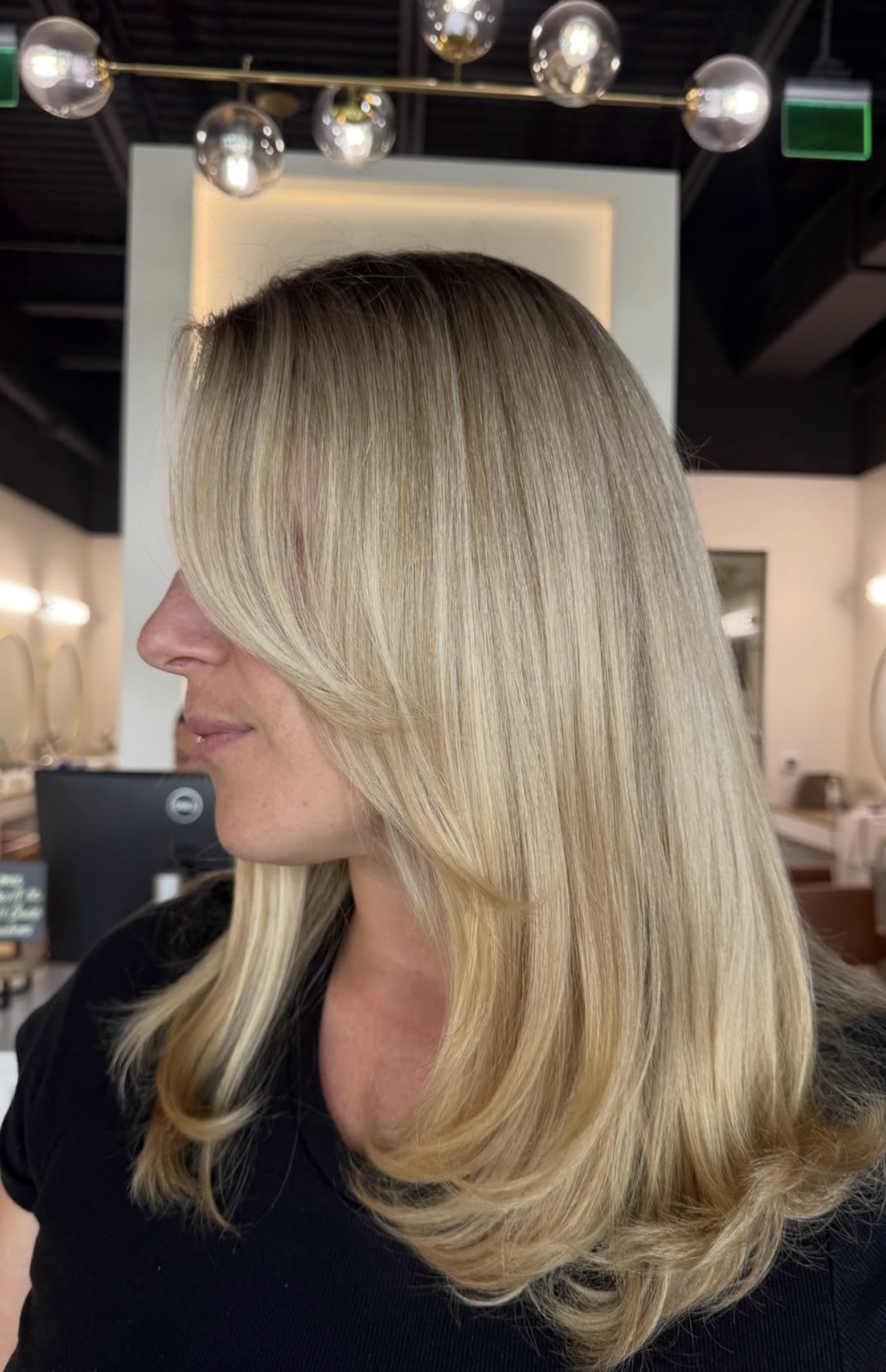 Polished dimensional blonde with long layers by Monica at AMAVI Salon